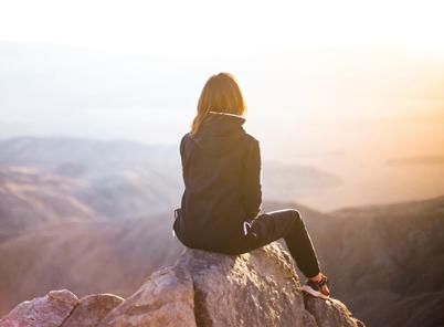 femme assise sur un sommet rocheux, contemplative